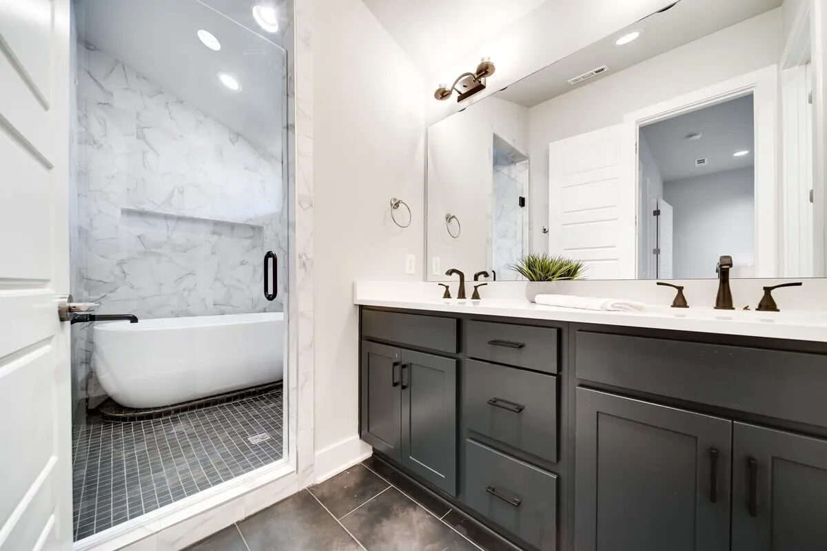 A luxurious, spa-like ensuite bathroom with a freestanding bathtub, dual sink vanity, large mirror, and a glass-door shower. The atmosphere is serene and indulgent, ideal for unwinding after a busy day.