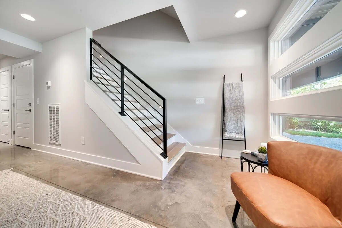 A contemporary seating area next to a staircase, featuring a decorative plant and cozy reading nook. The open layout hints at the home's connection to the outside and the welcoming atmosphere for guests.