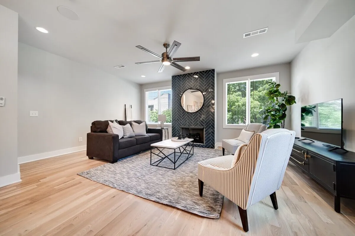 A cozy, contemporary living room with a comfortable sofa, coffee table, fireplace, large mirror, and a touch of greenery. The space invites relaxation and togetherness for families.