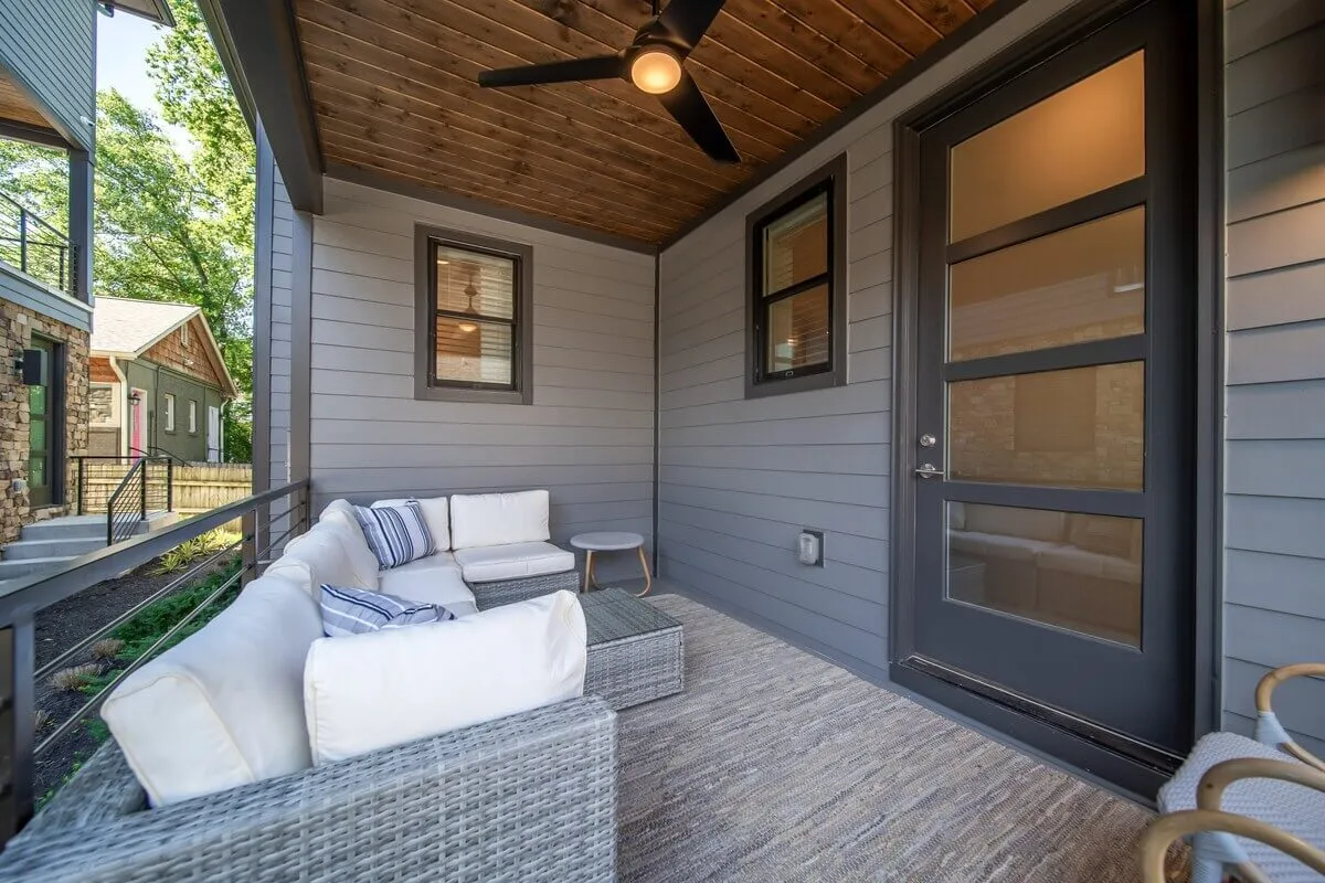 A cozy outdoor seating area featuring a sofa, ceiling fan, and an outdoor rug—ideal for relaxing, reading, or hosting intimate gatherings. The atmosphere is peaceful and encourages relaxation, with hints of evening light suggesting sunset views and tranquil moments.