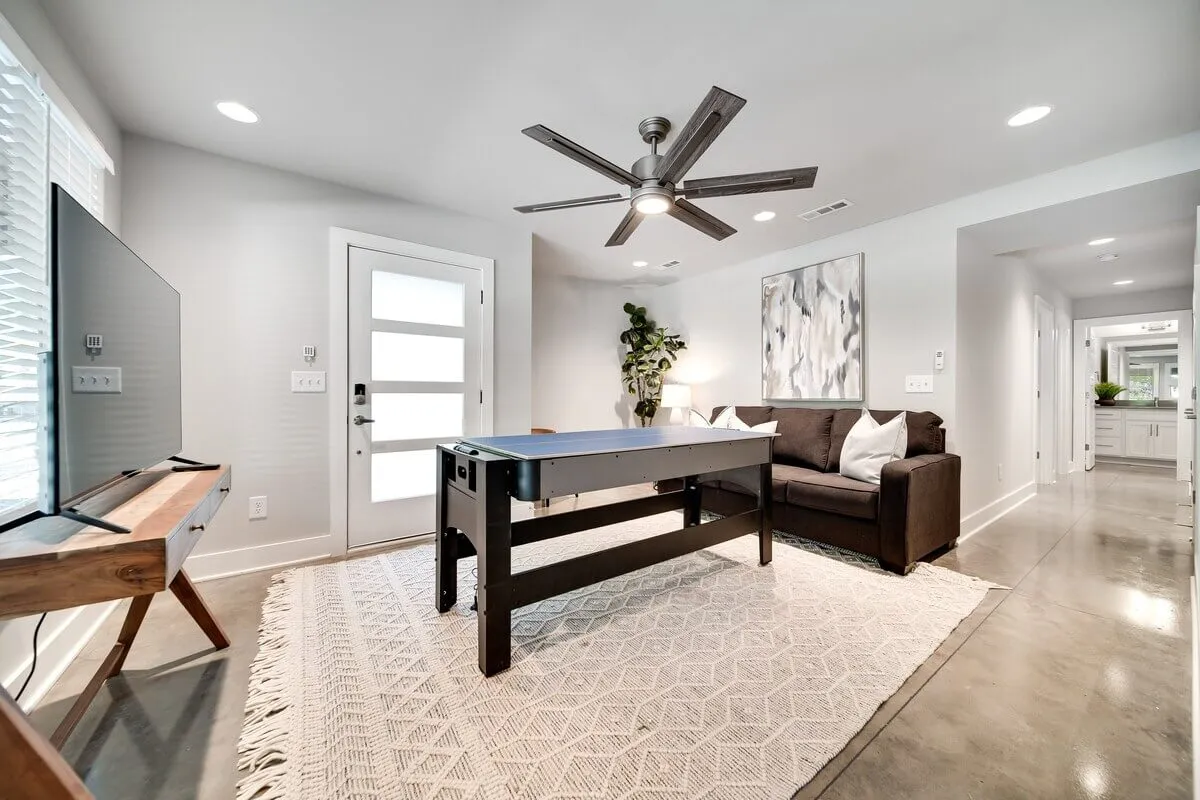 This image features an air hockey table in a cozy living space, complete with a sofa, wall-mounted TV, and contemporary artwork. The atmosphere is lively and relaxed, ideal for socializing or unwinding after a big game. The layout suggests ample room for group activities and a fun, communal ambiance.